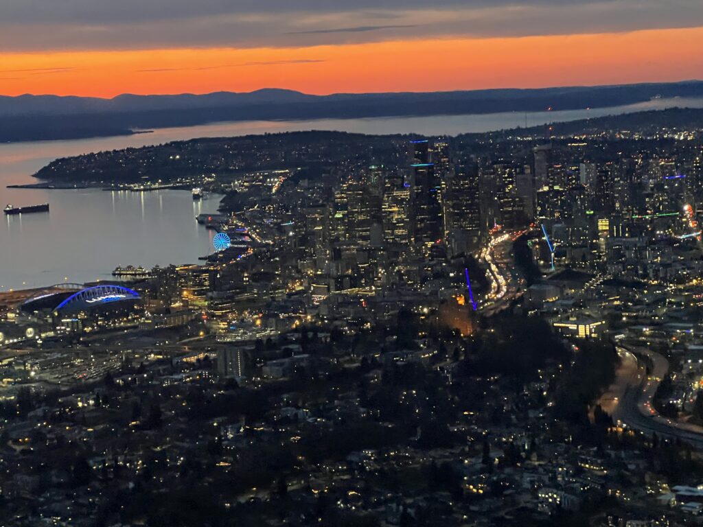 Aerial photo looking back over downtown Seattle with the waterfront, the Big Wheel, Lumen field and the Olympics - 29 March 2023 by Daryl Greaser